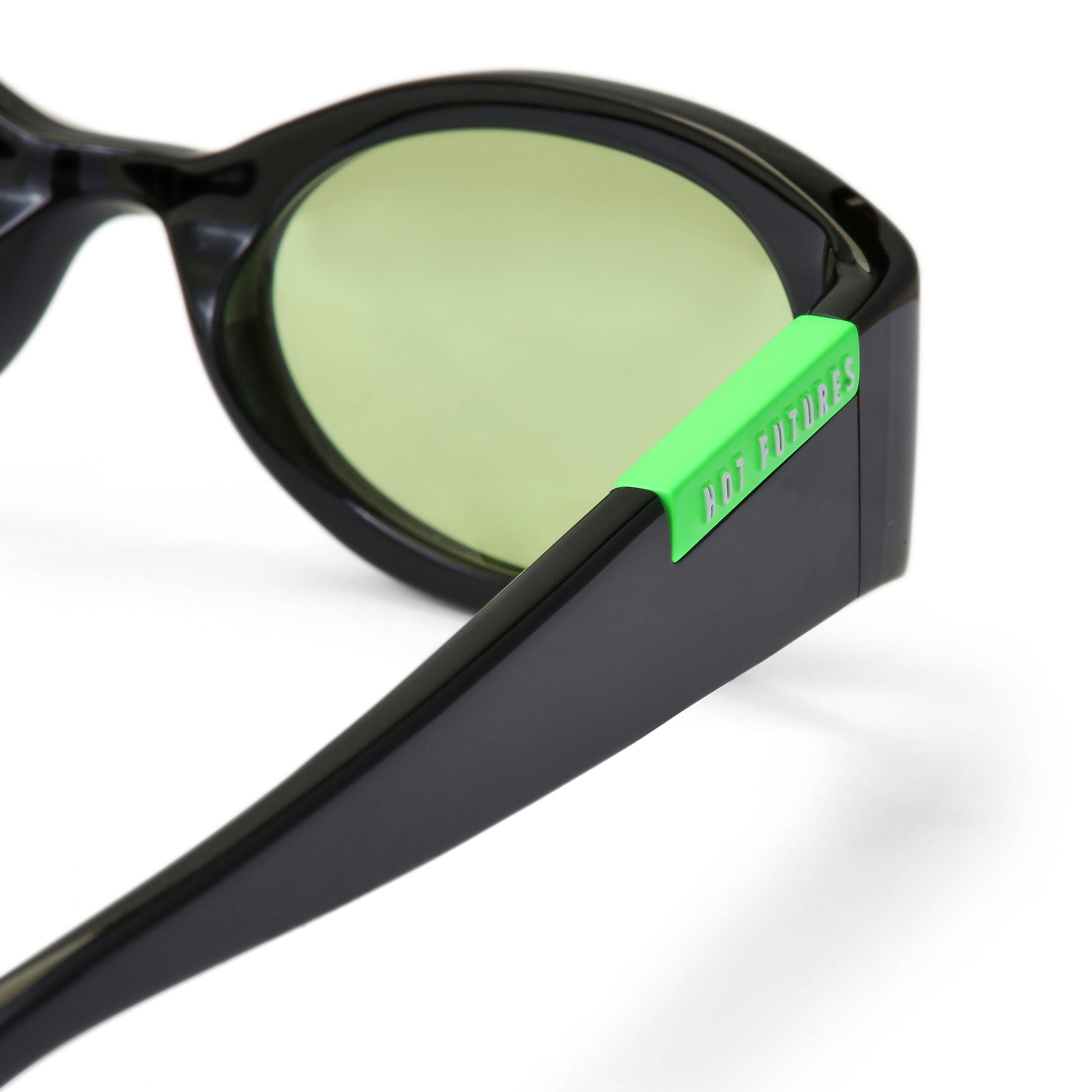 Close up shot of the baby racer glossy black sunglasses with green lenses.