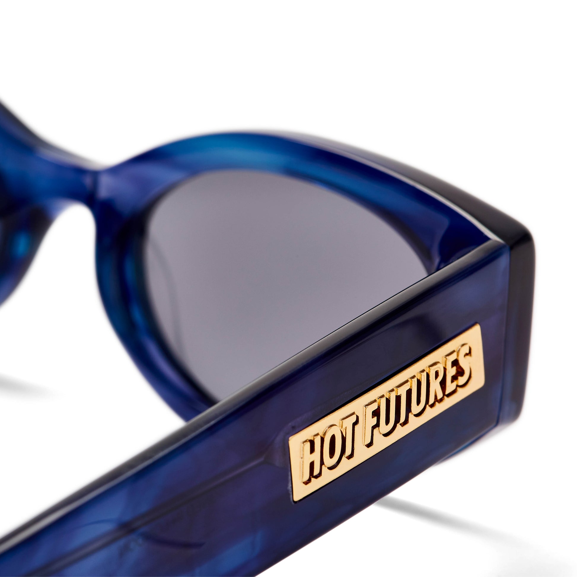 close up shot of the crystal blue frame cosmic rebel sunglasses with a dark smokey lens and gold Hot Futures branding on the arm
