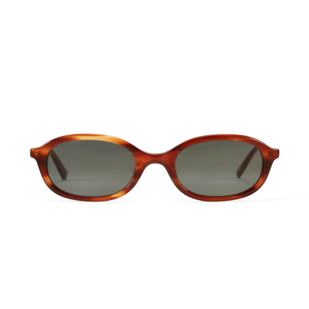 A pair of oval-shaped sunglasses with a caramel tortoiseshell acetate frame and dark green lenses.