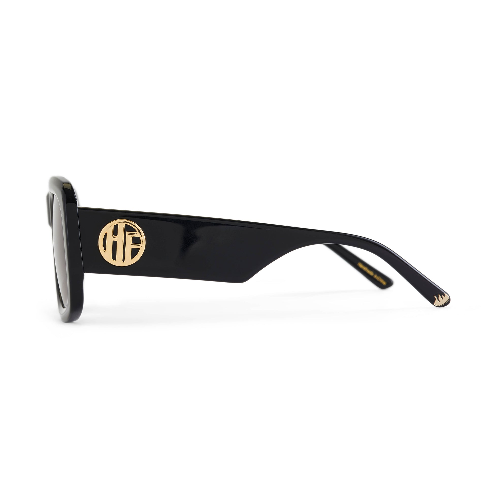 A pair of glossy black acetate flat top large sunglasses with dark smoky tinted lenses, with the gold Hot Futures branding shown on the arms