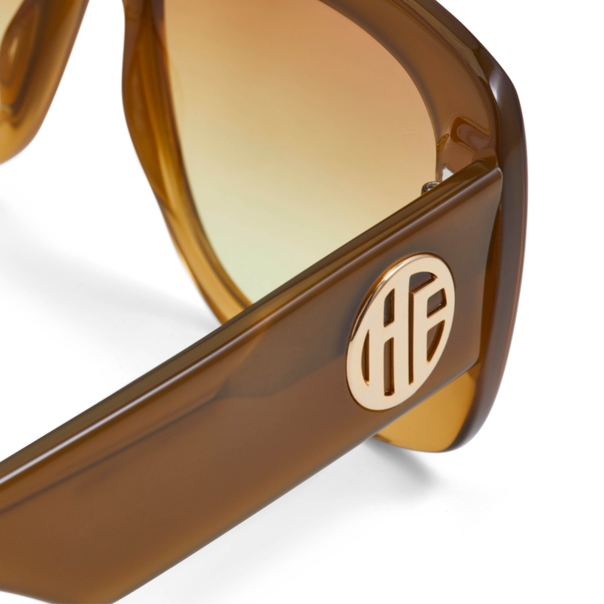 Close-up of brown sunglasses with the Hot Futures gold logo on the frame against a white background