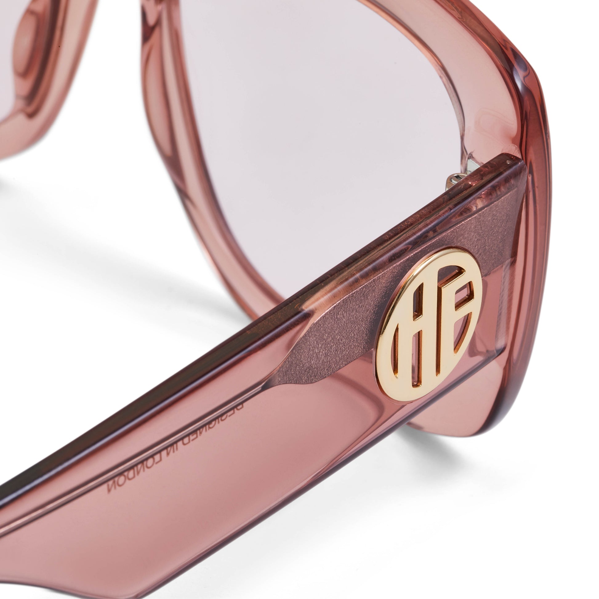 A pair of rose pink acetate flat top large sunglasses with pink tinted lenses, with the gold Hot Futures branding shown on the arms