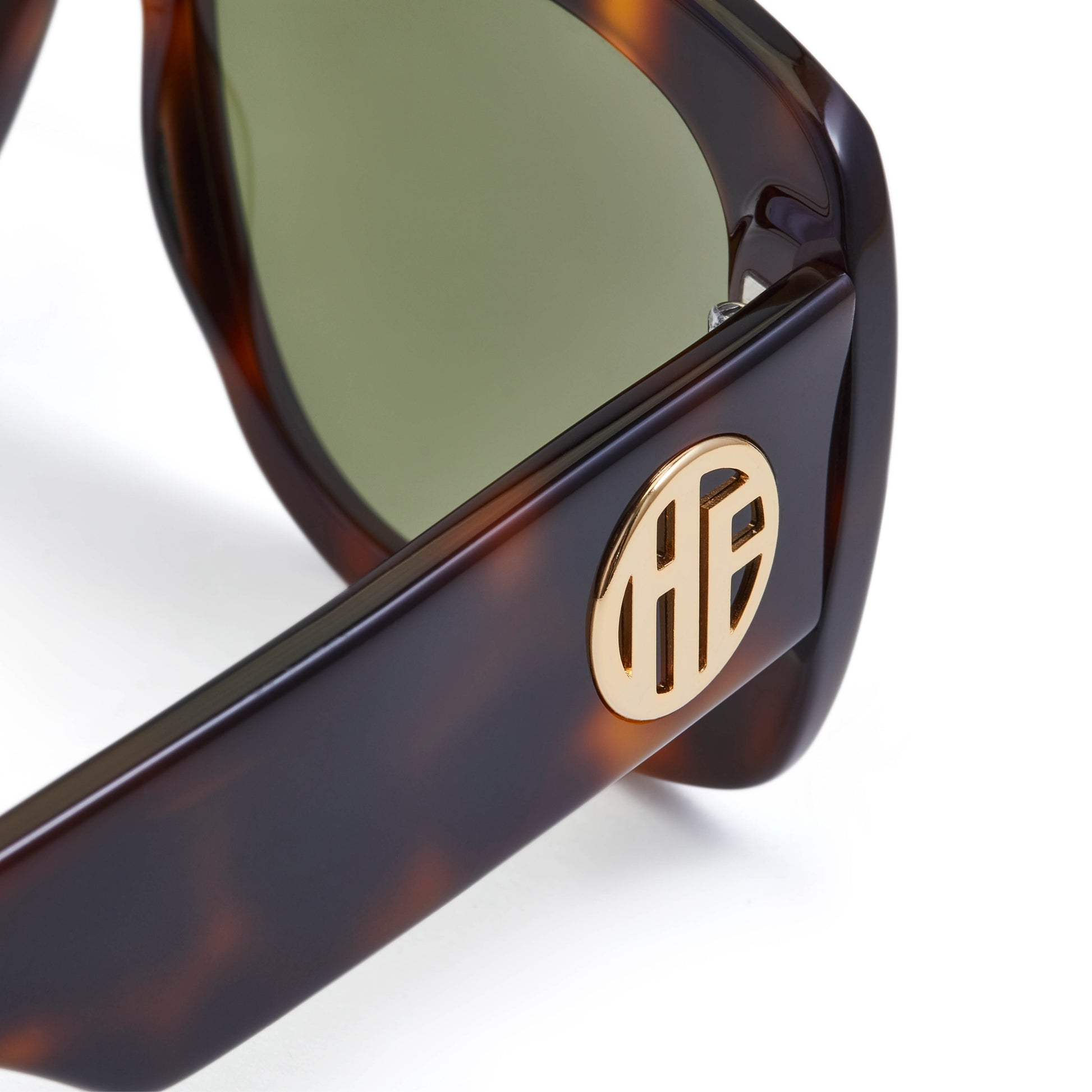 A pair of flat top acetate frame sunglasses with green tinted lenses and tortoiseshell pattern frame detailing. With gold Hot Futures logo branding to the arms.