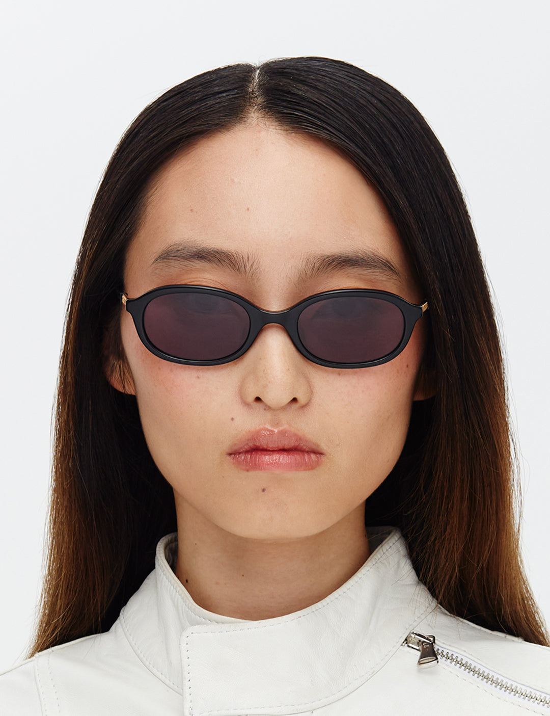 A pair of black oval sunglasses with smoke-coloured lenses, designed in a 90's revival style.
