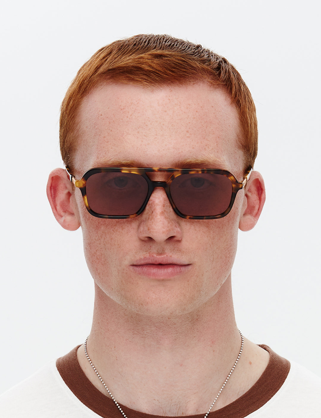 A pair of tortoiseshell patterned sunglasses with a slim rectangular aviator frame